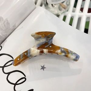 Close-up of tortoise shell acetate claw clip with colorful rhinestones on a magazine