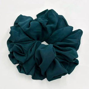 Detail of a large dark green chiffon scrunchie with soft textured fabric pleats