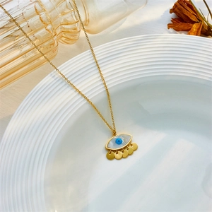 Detail of 18K gold butterfly necklace with white shell and devil eye on ceramic tray