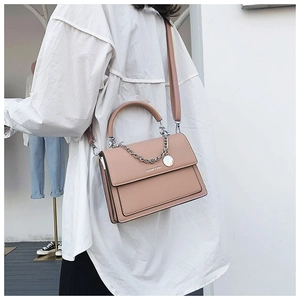 Detail of mauve leather flap bag with silver chain strap shown worn by a model