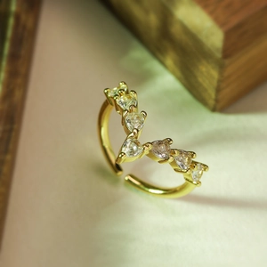 Detail of V-shaped gold ring featuring heart-cut clear zircons and adjustable band