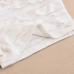 Vue détaillée des volants blancs et de la texture en coton et lin sur cet ensemble chic