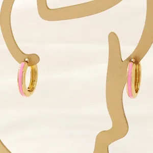 Detail of 18K gold-plated hoop earrings with pink enamel finish on gold metal stand