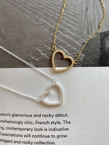 Detailed macro shot of gold and silver open heart pendants with zircon pave settings