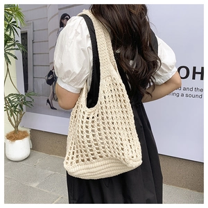 Detail of beige hollow knit tote bag showing thick shoulder strap and woven texture