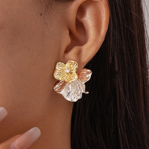 Nahaufnahme eines zweifarbigen Metallblumenohrrings mit Zirkon am Modellohr