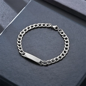 Polished silver cuban link bracelet with a rectangle id plate on a grey gift box
