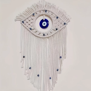 Detail of handmade macrame evil eye wall hanging with blue glass bead and cotton tassels