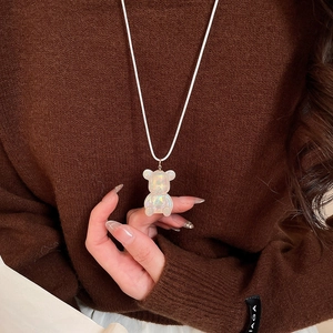 Macro shot of an iridescent resin bear pendant necklace worn over a brown sweater