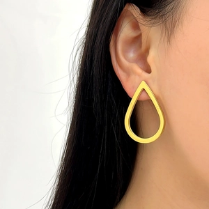 Vintage hollow water drop earrings in gold finish worn by model in a side profile shot