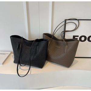 Close-up of black and taupe woven tote bags with elegant minimalist faux leather texture