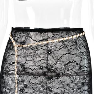 Detail of black lace skirt with white and gold chain belt on transparent mannequin