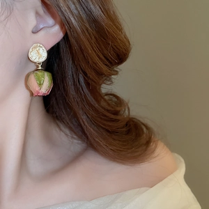 Close-up of golden rose pendant earring featuring pink and green gradient floral design