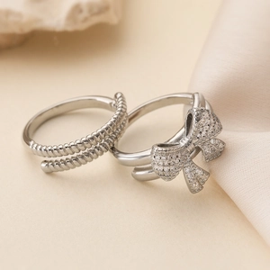 Close-up of 18K gold-plated bow ring set with white zircons and silver rope band