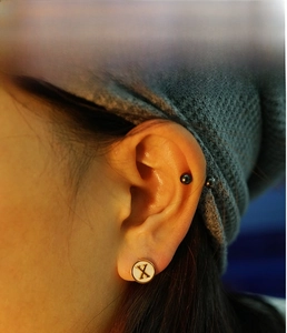 Detail shot of letter X stud earring with white shell inlay and 18K gold plated steel
