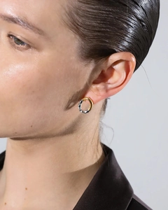 Close-up of dual-tone 18K gold and silver textured round earrings worn by a model