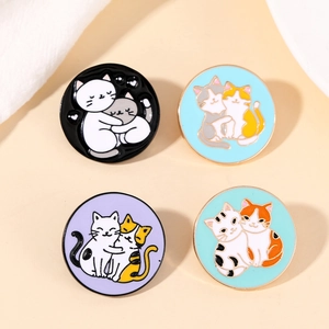 Close-up of four colorful enamel cat pins on soft fabric background with natural lighting