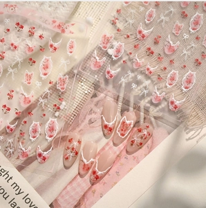 Macro detail of French floral and lace bow nail stickers on soft pink manicured nails