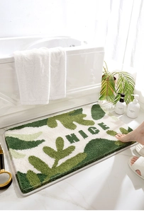 Dettaglio di un morbido tappeto da bagno verde e bianco con design floreale NICE