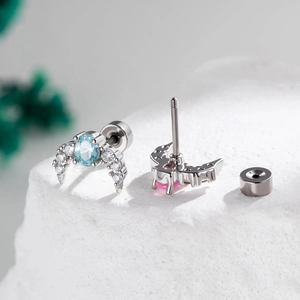 Elegant crescent moon screw-back cartilage studs with blue gemstones on stone display