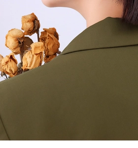Macro shot of olive green blazer fabric showing fine twill texture and shoulder stitching