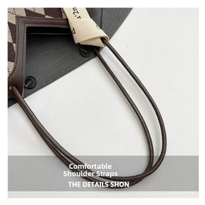 Close-up of brown checkered canvas bucket bag with leather trim and lettered strap details