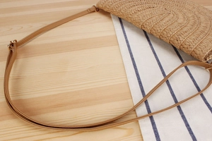 Detailed macro view of woven paper rope texture and golden hardware on beach bag