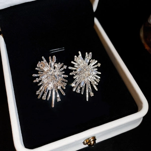 Macro detail of silver firework stud earrings with sparkling crystals on black velvet