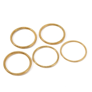 Set of five minimalist gold stainless steel bangles featuring various textured spiral designs