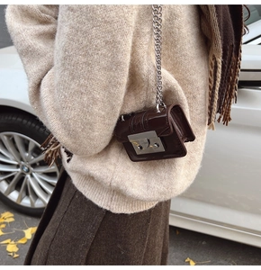 Close-up of mini dark brown patent leather crossbody bag with silver buckle and chain
