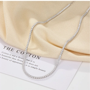 Close-up of silver tennis necklace with sparkling cubic zirconia on gold satin fabric