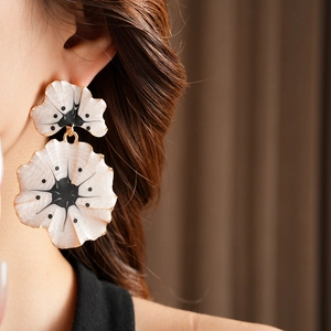 Gros plan de boucles d'oreilles vintage ginkgo émaillées avec bord doré sur un mannequin