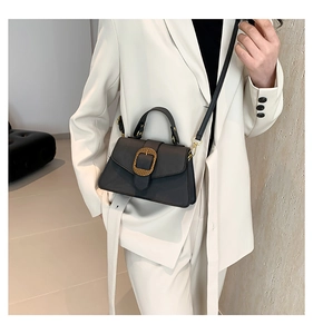 Close-up of vintage black faux leather handbag with gold textured oval buckle detail