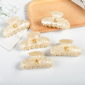 Pinces à cheveux en acrylique marbre crème avec lettres dorées sur plateau en bois