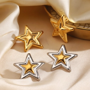 Chic star stud earrings in gold and silver finish on a silk background