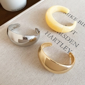Détail de bracelets joncs minimalistes en or, argent et résine de couleur crème