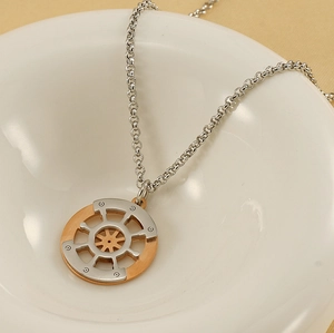 Detailed close-up of dual-tone compass pendant on a ceramic dish with textured fabric