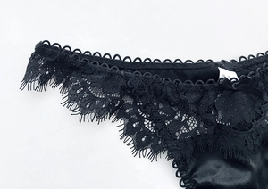 Primo piano dell'elegante pizzo nero e del raso setoso su questo perizoma da donna