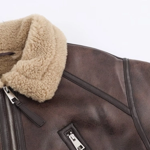 Detail shot of brown leather flight jacket showing silver zipper and plush sheepskin collar