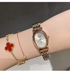 Close-up of elegant rose gold oval quartz watch worn on wrist with metal strap