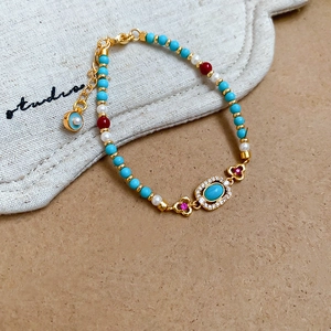 Detail of turquoise and pearl beaded bracelet with a zircon-encrusted centerpiece charm