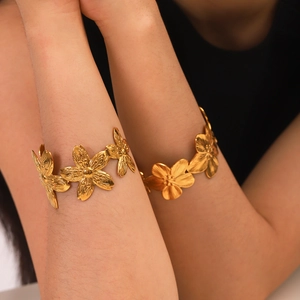 Dettaglio di due bracciali in acciaio inossidabile oro 18K con motivi a petali floreali