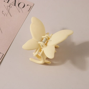 Détail de la pince à cheveux papillon jaune crème avec finition mate et ressort métal