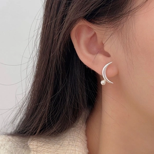 Detail of a minimalist 925 silver crescent moon stud earring with a pearl on a model