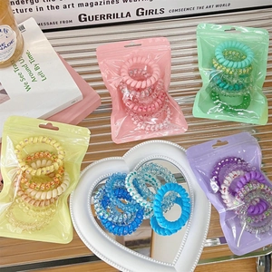 Close-up of spiral hair ties in pastel gradient colors packed in individual clear pouches