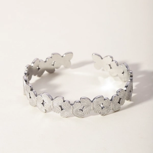 Macro detail of silver-colored butterfly-shaped textured metal links on an open bangle