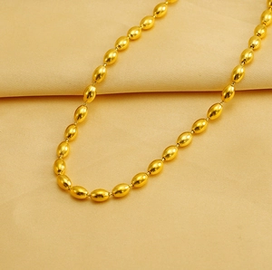 Macro detail of luxury golden olive-shaped bead necklace with polished metallic finish