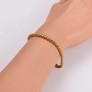 Elegant gold woven wheat chain bracelet in stainless steel shown on a model wrist