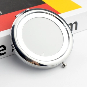 Close-up of a silver metal folding makeup mirror with a blank surface for customization