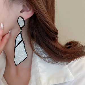 Detail of white marble acrylic geometric earrings on a model with a minimalist aesthetic